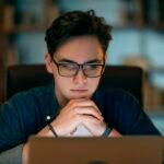 Focused IT worker looking at laptop screen, working late at office