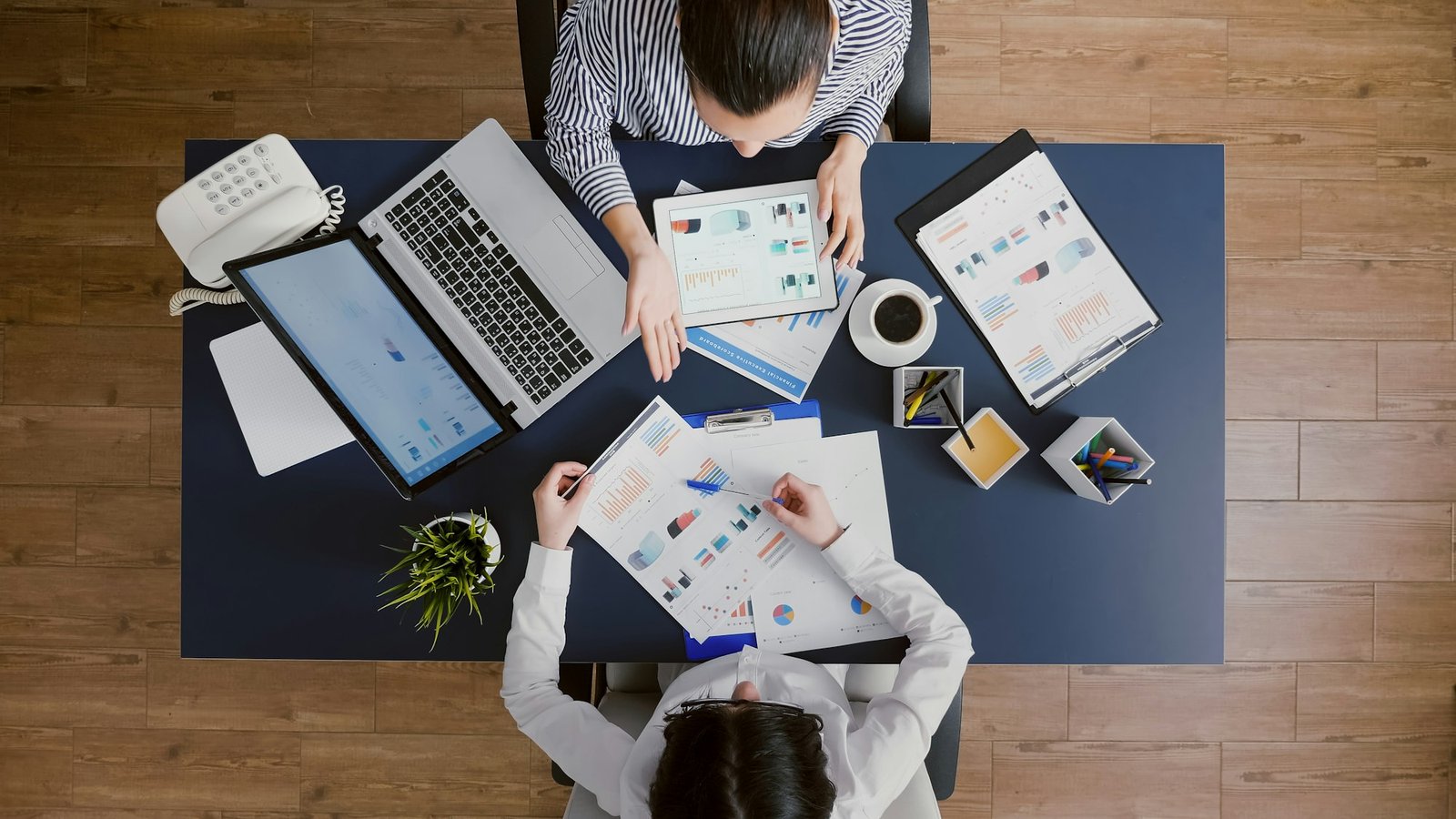 Top view of business women comparing financial graphs with management statistics expertise